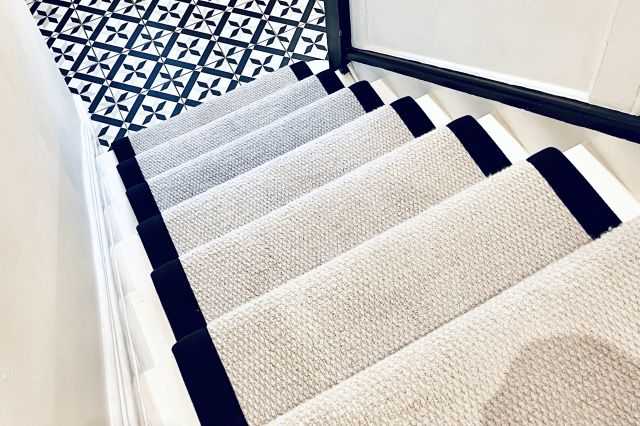 black and white tiled hallway with cream and black stair runner